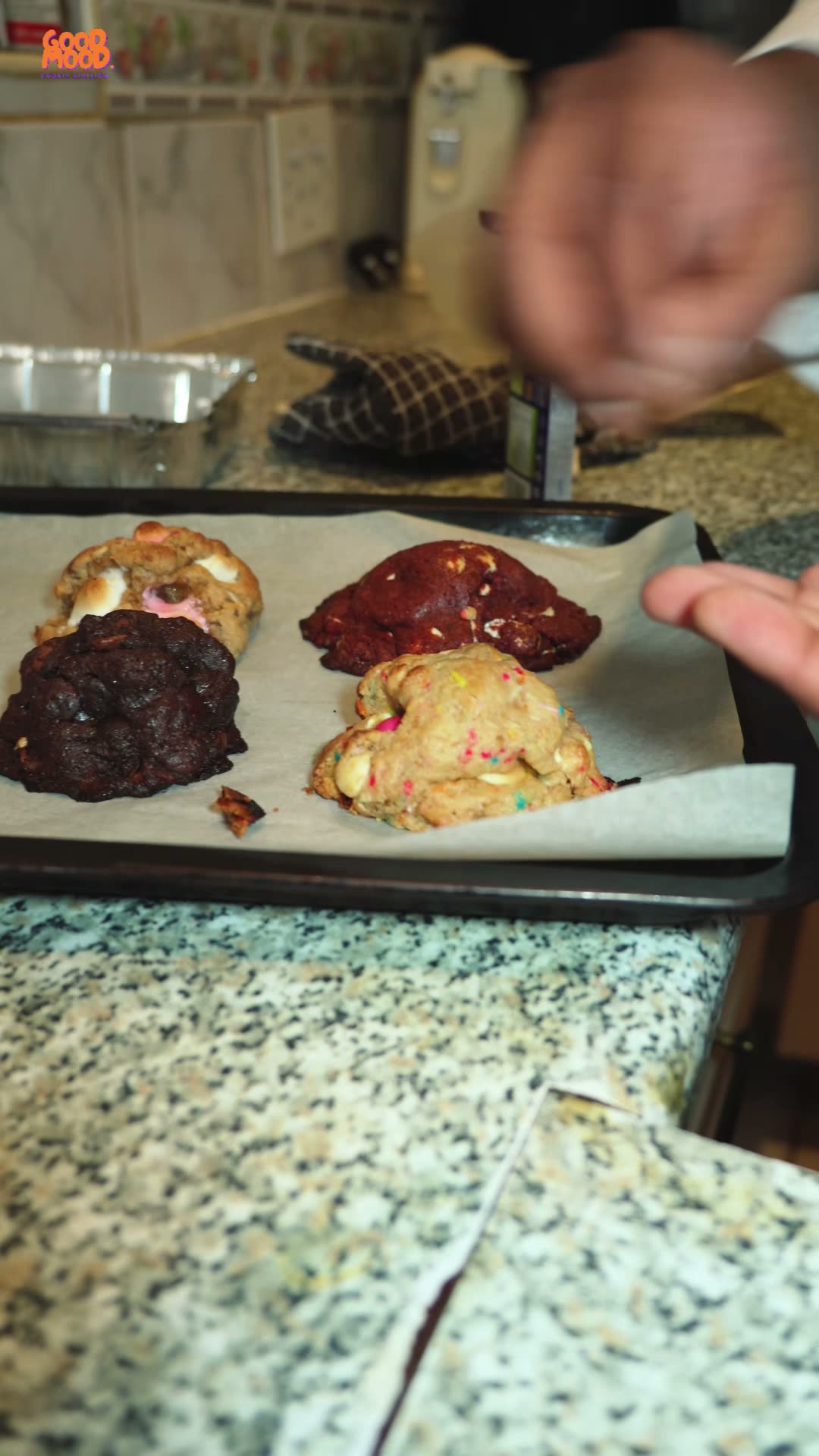 Fresh cookies on a baking tray beside a speckled granite counter.